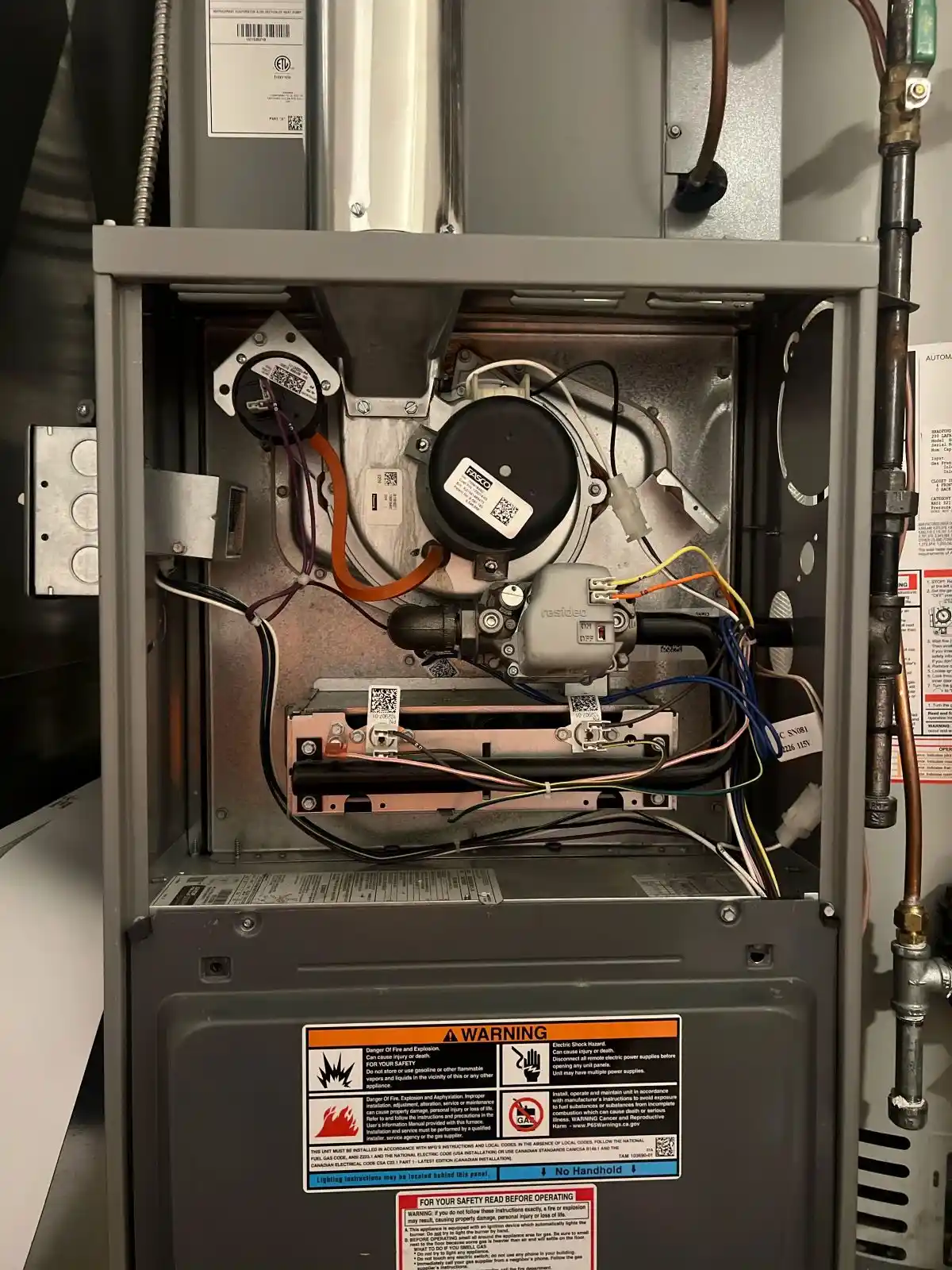 furnace-repair-heating-system-components-diagnosis Open residential gas furnace showing internal heating components, wiring, blower assembly, burners, and controls during furnace repair and diagnosis.