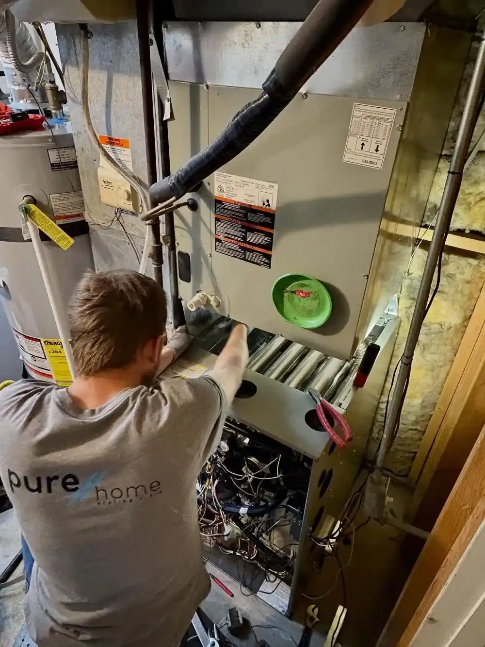 purehome-furnace-repair-technician-diagnosing-heating-system-herriman-utah PureHome Heating + Air technician performing a residential furnace repair and heating system diagnostic inside a Herriman, Utah home to restore safe, reliable indoor heat.